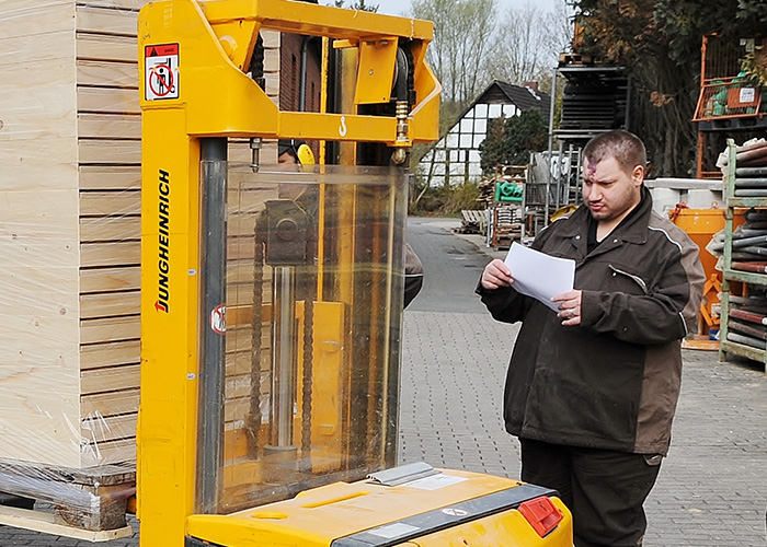 Mann mit Behinderung prüft waren an Gabelstapler