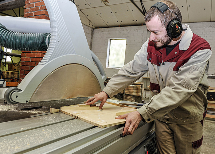 Mann an Fräsmaschine schneidet Holz