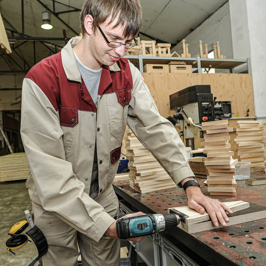 junger Mann bohrt in Holzplatten