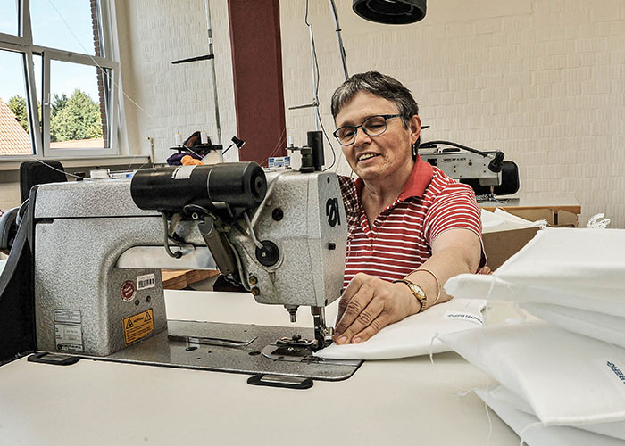 Frau sitzt an Nähmaschine