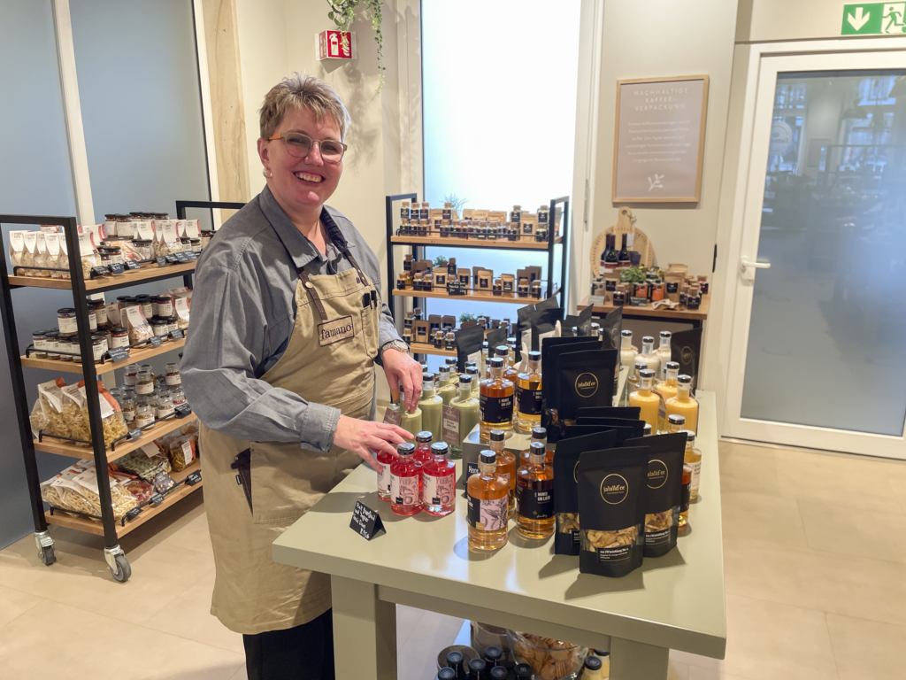 Beschäftigte steht am Tisch mit verschiedenen Verkaufsartikeln